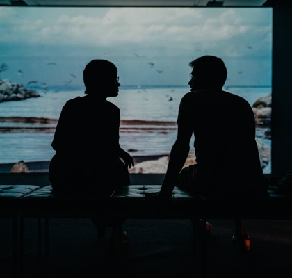 Silhouette of two people engaged in conversation